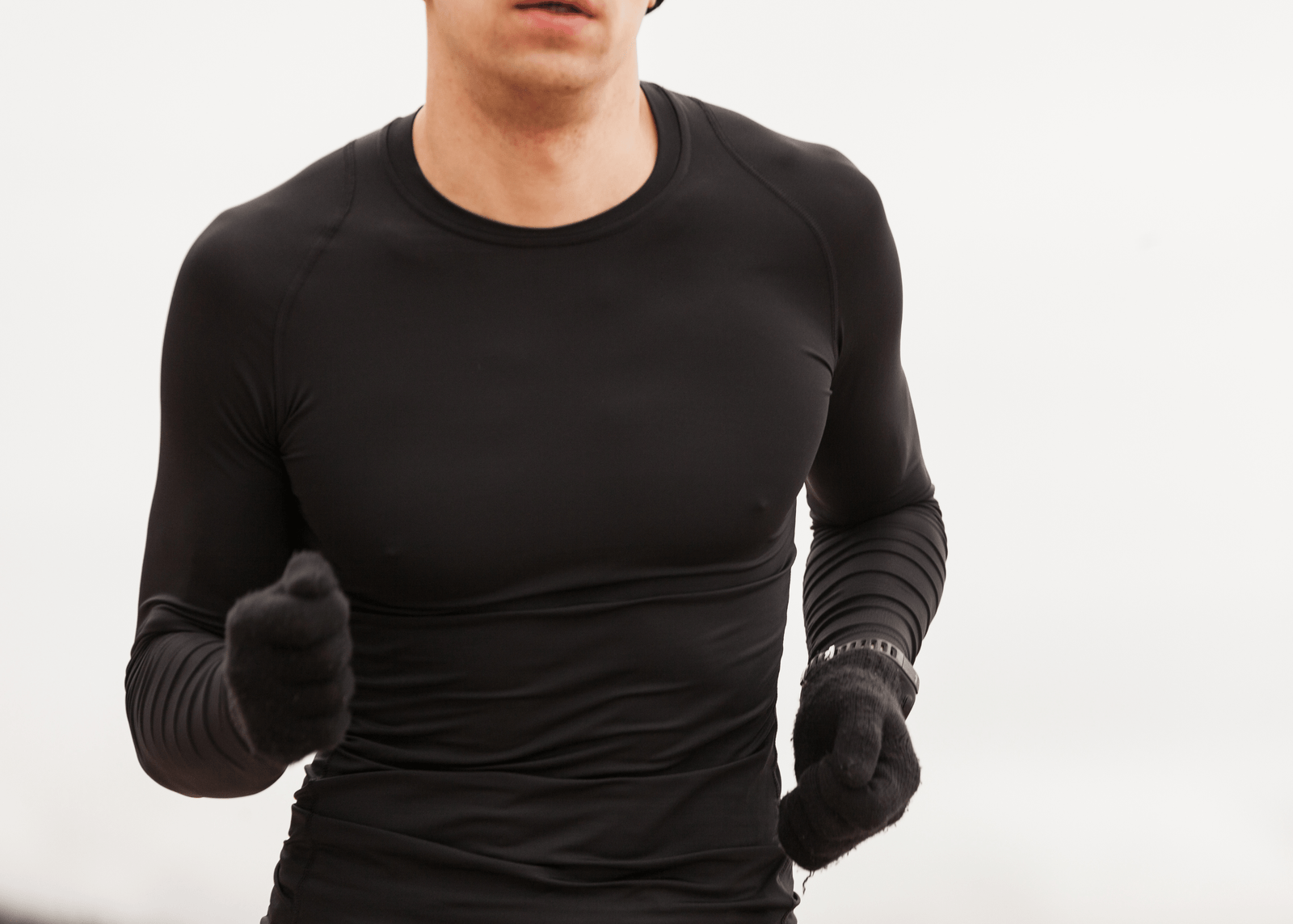 Hombre corriendo al aire libre con camiseta térmica negra de manga larga, ideal para entrenar y jugar en clima frío y mantener el calor corporal.